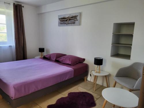a bedroom with a purple bed and a chair at Le Clos des Figuiers - 3 Gîtes de caractère in Duravel