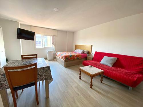 a living room with a red couch and a bed at Hostel Penedes in Vilafranca del Penedès