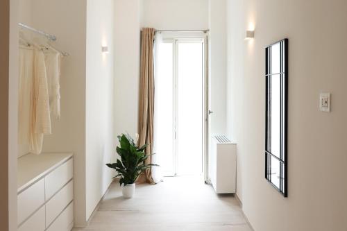 a white hallway with a large window and a plant at IL GELSO BIANCO Luxury apartments in Polignano a Mare