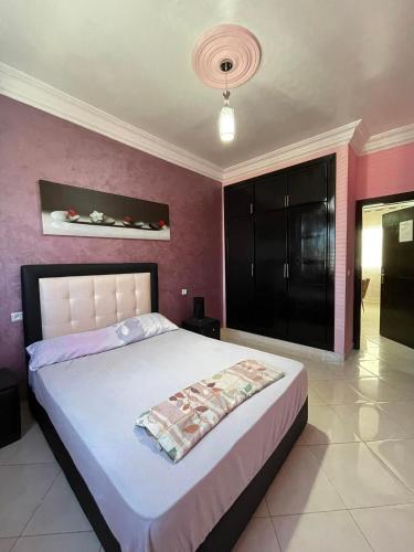 a bedroom with a large bed and a pink wall at Apartement 3 residence oulad touimi in Martil