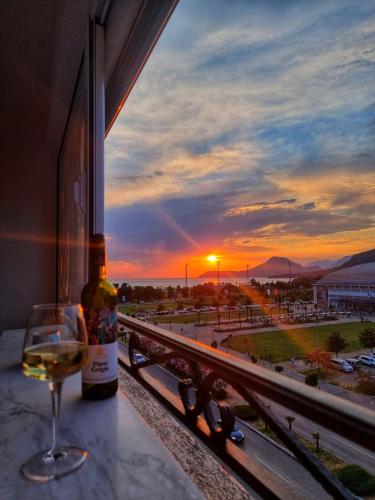 a bottle of wine and a glass on a window sill with a sunset at Baby Blue Apartments in Bar