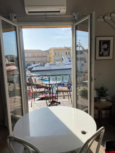 a table and chairs on a balcony with a view of a boat at Le Petit Bijou Sète, quatre appartements au centre ville, trois avec vue canal in Sète