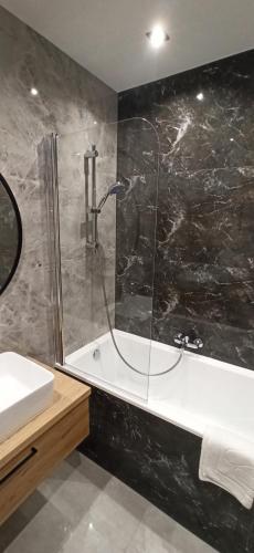 a bathroom with a shower and a tub and a sink at Apartament Zamkowe Wzgórze in Lidzbark Warmiński