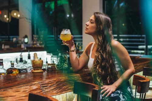 a woman sitting at a bar holding a glass of beer at The Ellysian Boutique Hotel in Placencia Village