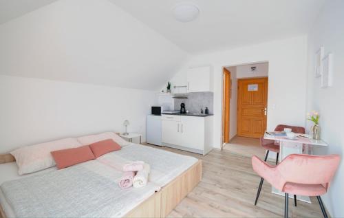 a bedroom with a bed with pink chairs and a kitchen at Villa Tara Bük in Bük