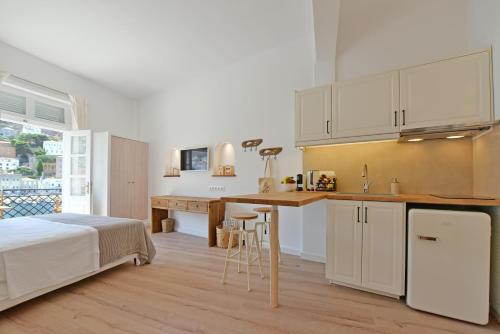 a bedroom with a bed and a kitchen with white cabinets at Estia Hydra in Hydra