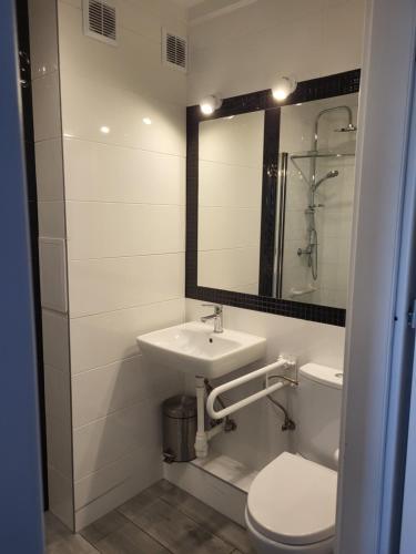 y baño con lavabo, aseo y espejo. en Apartament na Skwerku, en Gdynia
