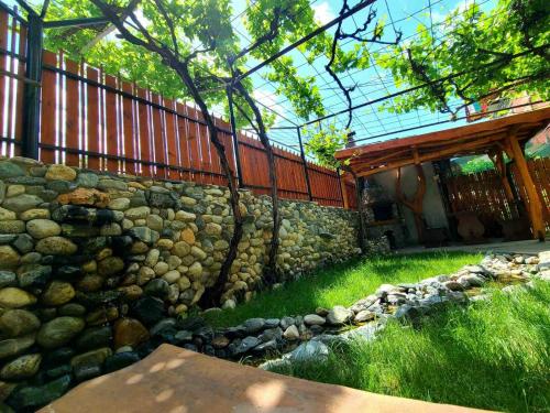 a stone wall in front of a house with a creek at Вила 111 in Sapareva Banya