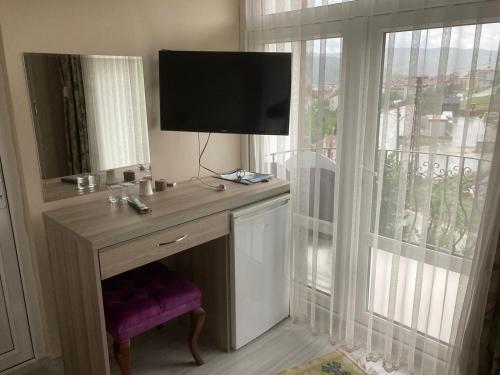 a room with a desk with a tv and a window at SARIMESE OTEL in Demirci
