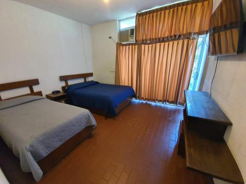 1 dormitorio con 2 camas, mesa y ventana en HOTEL PLAZA en La Paz