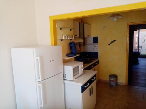uma cozinha com um frigorífico branco e um micro-ondas em Séjour Valras-Plage T3 Vue sur Mer - 50m centre et mer em Valras-Plage