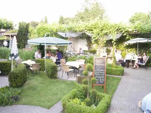 a group of people sitting at tables in a garden at Hotel Restaurant Esser in Wegberg