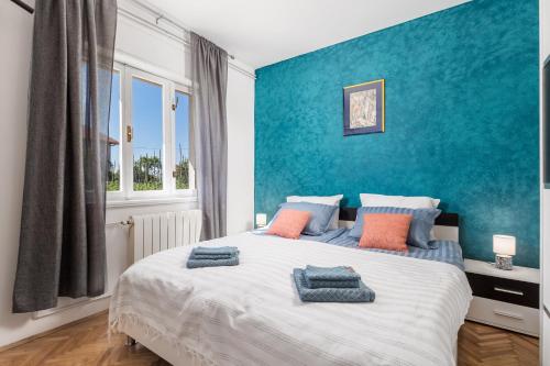 a bedroom with a large bed with blue walls at Zen 6 in Viskovo