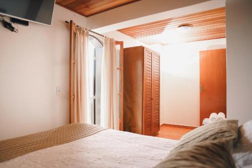 a bedroom with a bed and an open door at Pousada das Pedras in Monte Verde