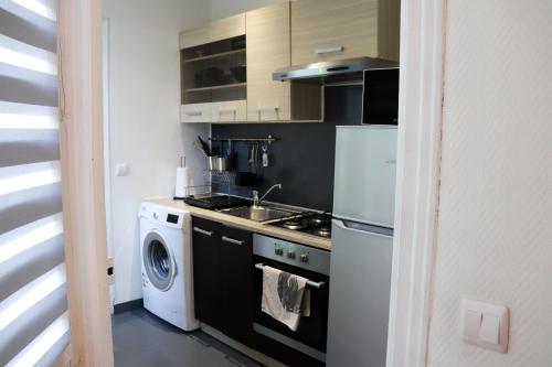 een keuken met een fornuis en een wasmachine bij THE VINTAGE APARTMENT AU COEUR DE LA VILLE DE RIMBAUD in Charleville-Mézières