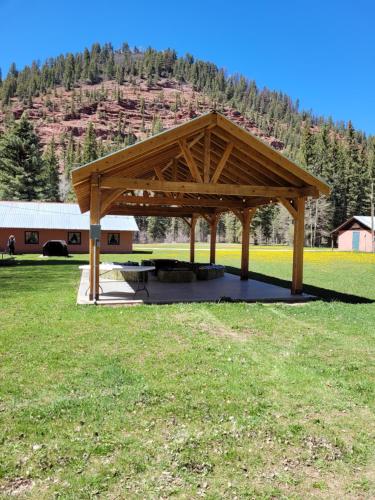 a wooden pavilion with a picnic table in a field at Circle K Ranch in Rico