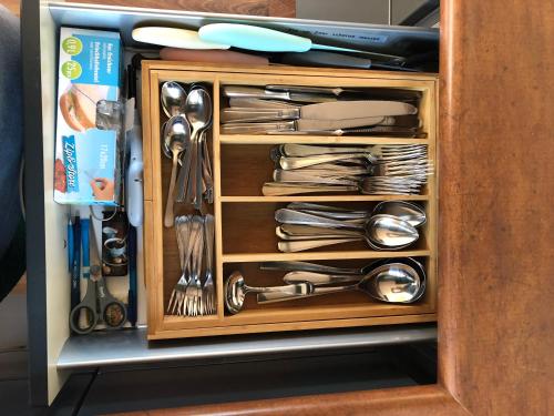 a cabinet filled with silver utensils at Chalet Bosrand 42 Park Veluwshof 6 p in Hoenderloo