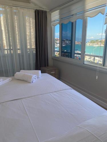 a bedroom with a large white bed with large windows at VENÜS PARK APART SUİTES in Çeşme