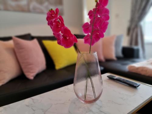 a vase with pink flowers sitting on a table at Virexxa Aylesbury Centre - Deluxe Suite - 3Bed House with Free Parking in Aylesbury