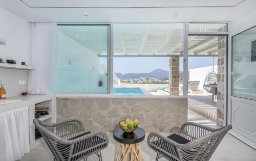 a kitchen and living room with two chairs and a table at Calma Suite Milos in Adamas