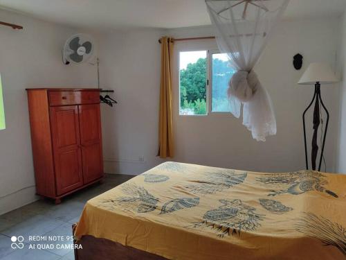 Un dormitorio con una cama y una cómoda y una ventana. en Guest House Bien-être créole, en Sainte-Anne