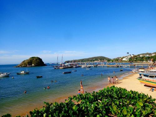 a beach with people in the water and boats at Pousada Porto Búzios in Búzios