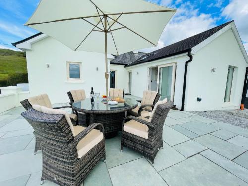 a patio with a table and chairs and an umbrella at Kathleen's Carrowkeel Cottage in Sligo