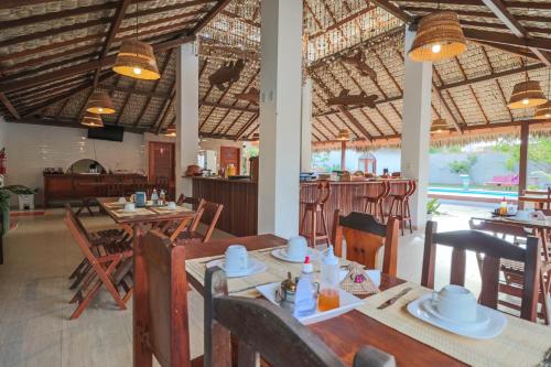 a restaurant with wooden tables and chairs and a bar at POUSADA IRMAOS ATINS in Atins