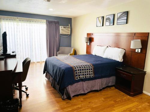 a hotel room with a bed and a desk at Bel Air Motor Hotel in Tustin