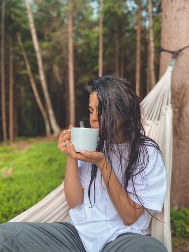 a woman sitting in a hammock holding a cup at Leśna Kąpiel in Karpacz