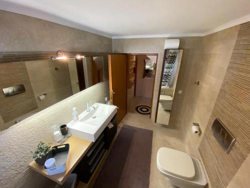 a bathroom with a sink and a toilet and a mirror at Voula’s dream house in Néa Péramos
