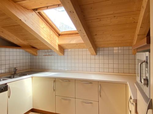 a kitchen with white cabinets and a skylight at Loft Mountain Spirit in Livigno