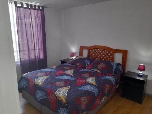 a bedroom with a bed with a colorful comforter and a window at Turismos brisa in Santiago