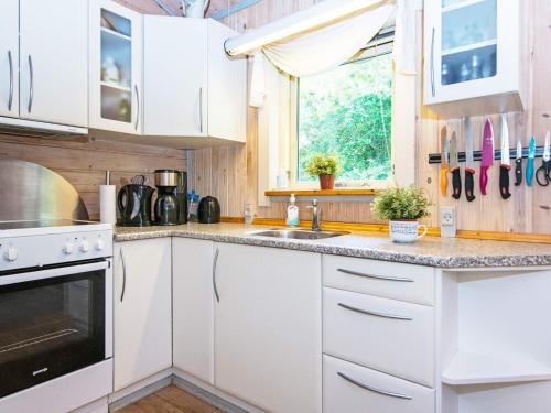 uma cozinha com armários brancos, um lavatório e uma janela em 6 person holiday home in Silkeborg em Silkeborg