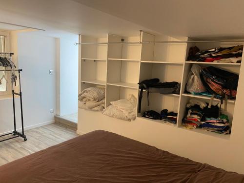 1 dormitorio con estanterías blancas y 1 cama en Bel appartement chez particulier calme et piscine, en Royan