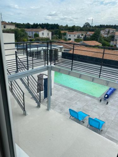 vistas a una piscina con 2 sillas azules en Bel appartement chez particulier calme et piscine, en Royan