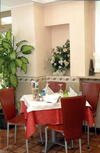 a dining room table with red chairs and a mirror at Hotel Da Angela in Sedegliano