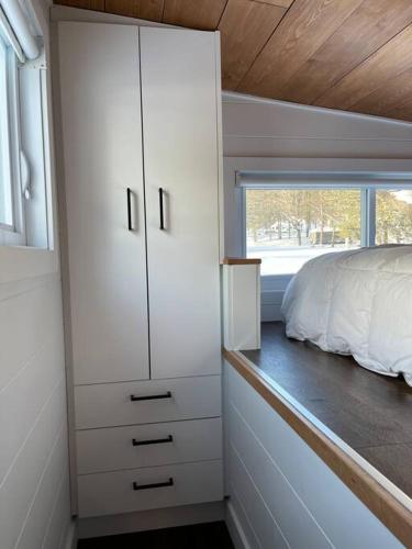 a bedroom with a bed and a large white cabinet at Mini maison La Charme in Saint Zenon