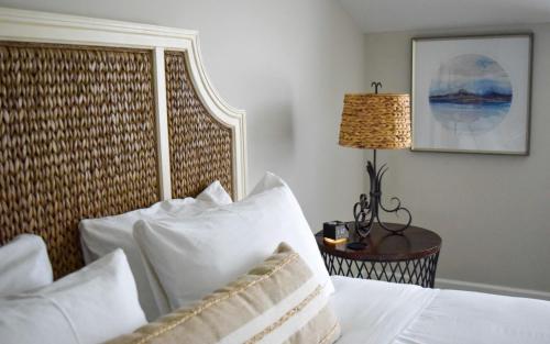 a bedroom with a bed with white pillows and a lamp at Tilghman Island Inn in Tilghman Island