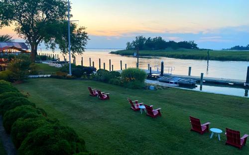a group of red benches sitting on the grass by the water at Tilghman Island Inn in Tilghman Island