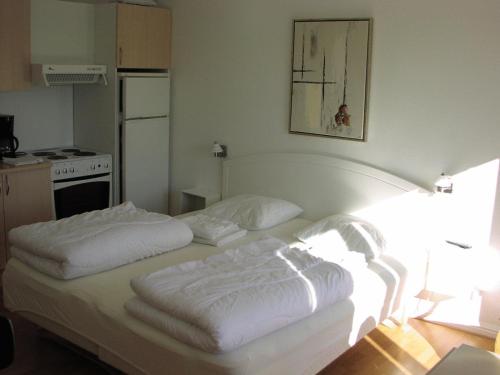 two white beds in a room with a kitchen at Skagen Apartment in Skagen