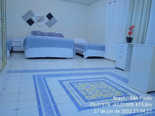 1 dormitorio con 2 camas y alfombra en el suelo en Acomodações Anfitriã, en Indaiatuba