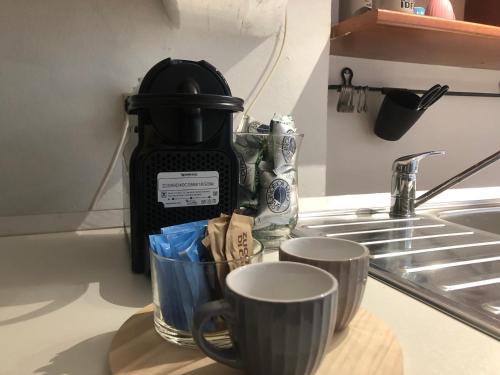 deux tasses sur un comptoir à côté d'une cafetière dans l'établissement Il tetto fiorito dell'Isola, à Milan