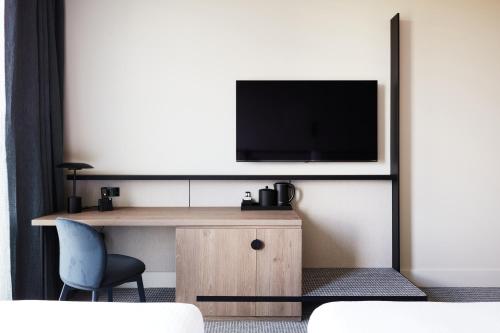 a room with a desk with a television on a wall at Hyatt Place Melbourne Caribbean Park in Scoresby