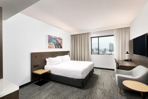 a hotel room with a bed and a chair at Holiday Inn West Perth, an IHG Hotel in Perth