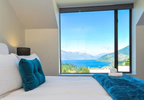 a bedroom with a large bed with a large window at Stunning Home with Amazing Wakatipu Lake Views in Queenstown
