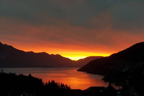 a sunset over a body of water with mountains at Stunning Home with Amazing Wakatipu Lake Views in Queenstown