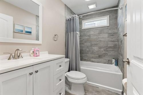 a white bathroom with a toilet and a sink at Spectacular 3 BR Condo One Block to the Beach in Brigantine
