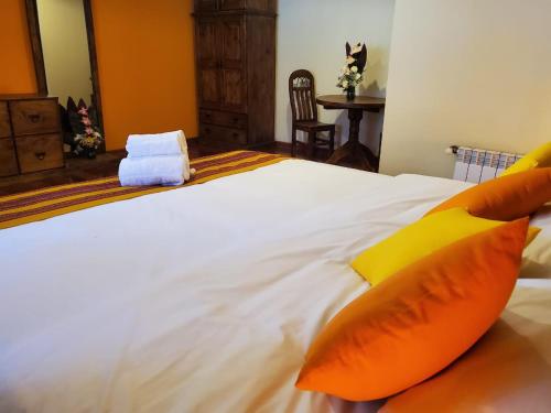 a bedroom with a large white bed with orange pillows at Patio de Piedra Hotel Boutique in La Paz