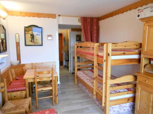 a room with two bunk beds and a table at Studio cosy skis aux pieds avec balcon et piscine chauffée - FR-1-267-205 in Le Corbier